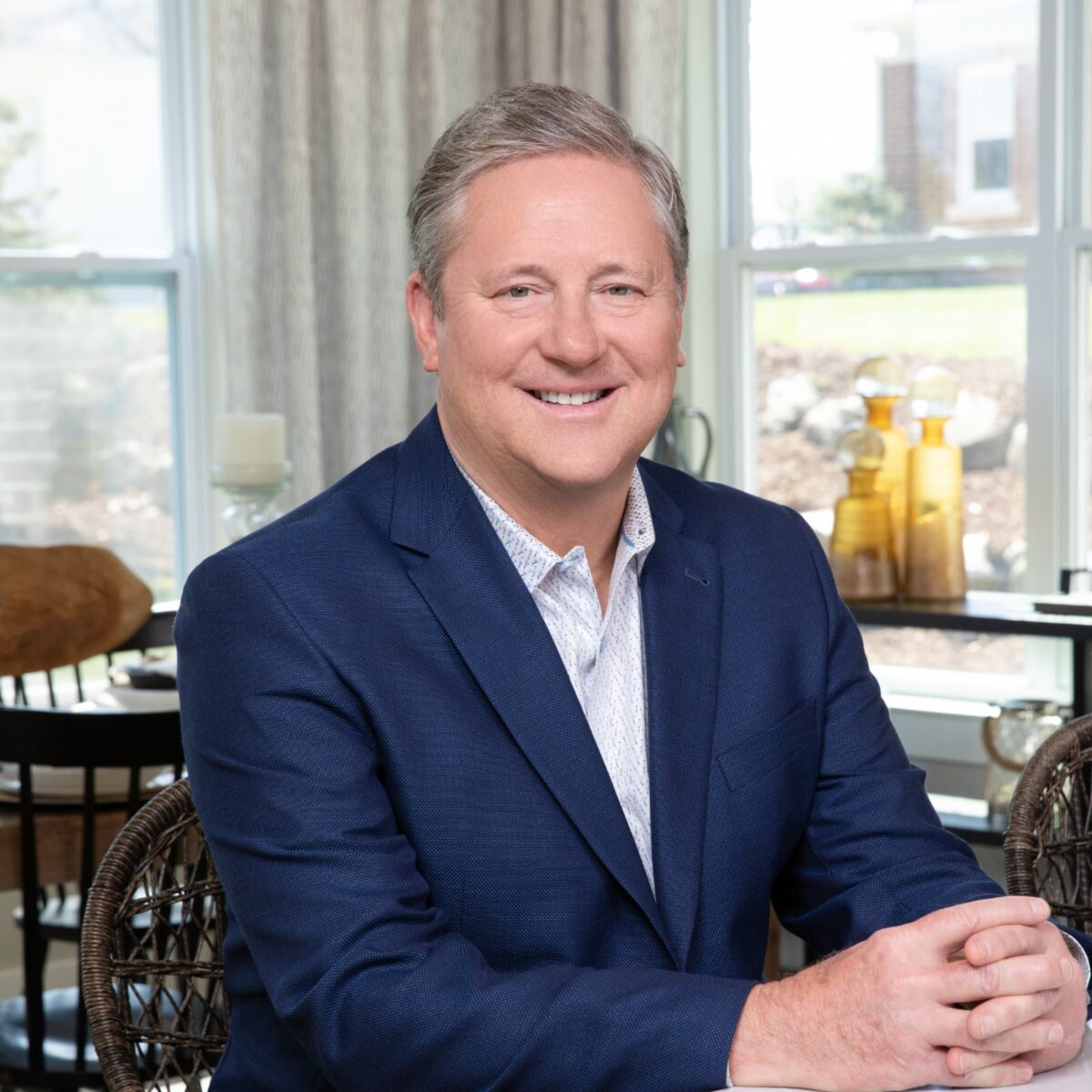 Todd Taliaferro, sitting in a modern kitchen wearing a blue suit smiling at the camera